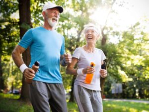 Active senior male and female couple jogging on outdoor path with waterbottles in their hands for article Active Adult and Senior Living in Phoenix for newcomers retiring in Phoenix.