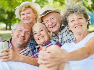 Close up of group of 5 seniors mix of 2 men and 3 women sitting outside posing for camera for article List of Senior Living Options in Phoenix for newcomers retiring in Phoenix.