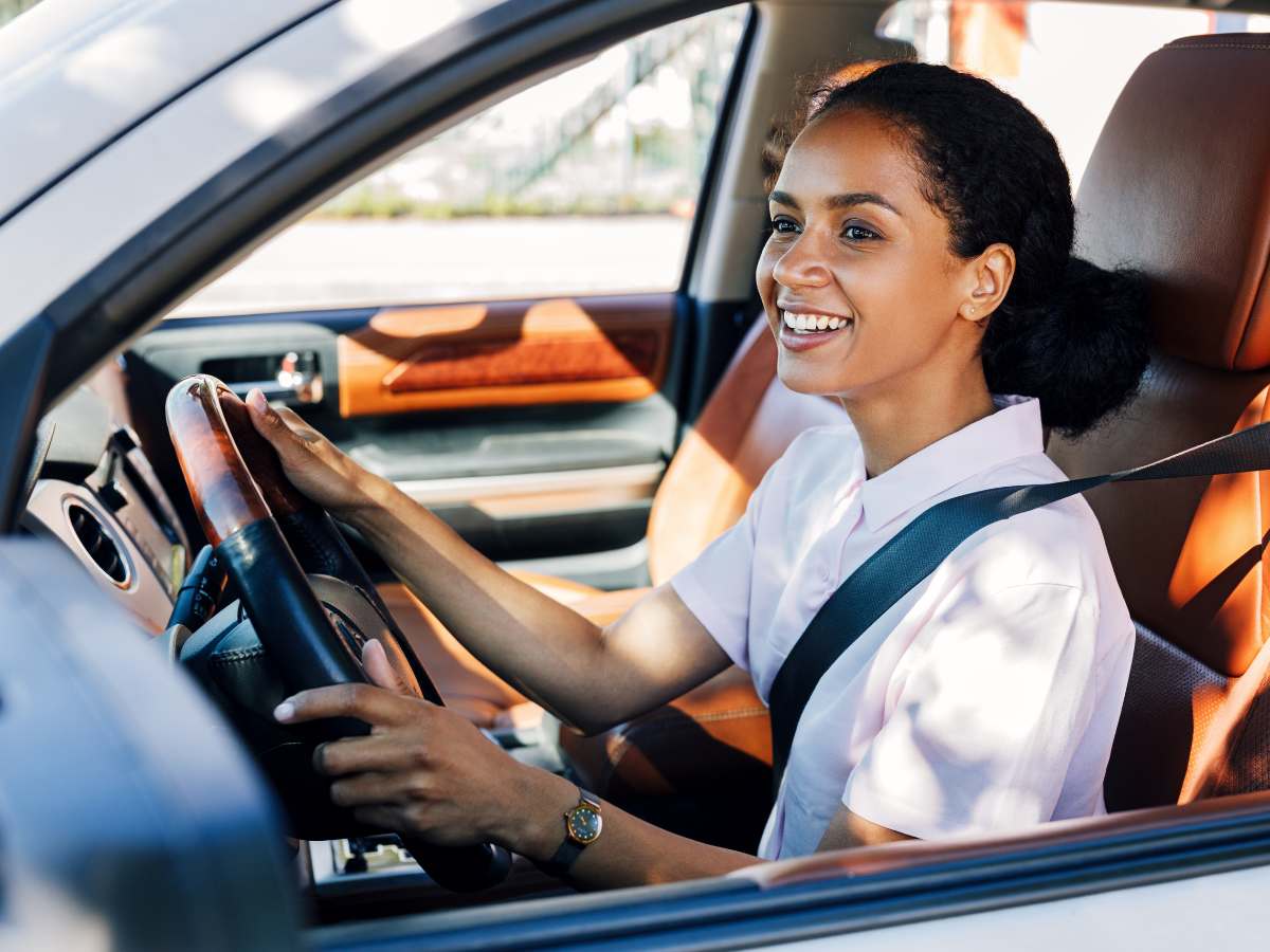 Woman sitting in drivers seat of car smiling for article Arizona Auto Insurance for newcomers moving to Phoenix.