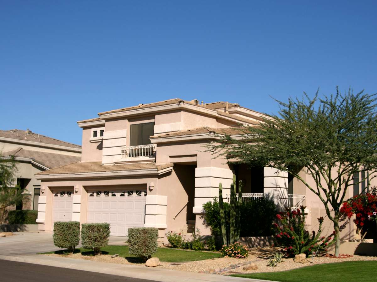 Home in Scottsdale, AZ - 2 story with 3 car garage, short driveway and stone entryway with a few shrubs and cacti beautifully landscaped for article Finding the Right Home in Phoenix for newcomers moving to Phoenix.