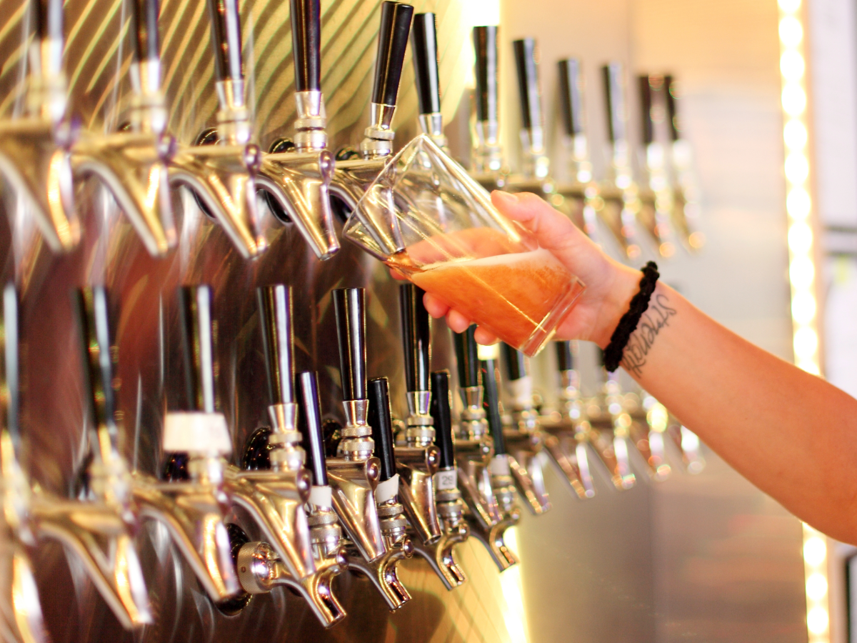 Wall of beer taps with a beer and a pint being filled.