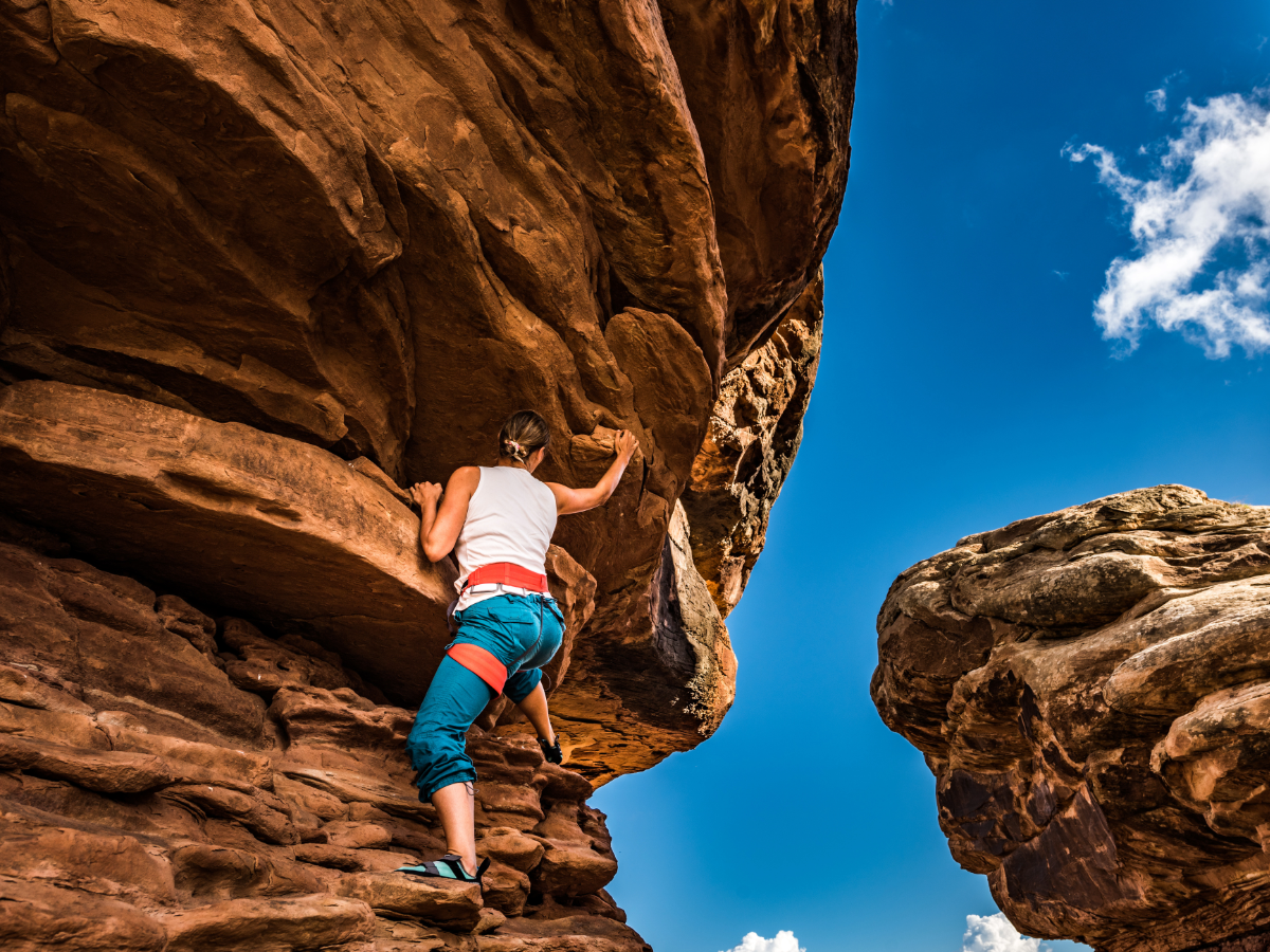 Woman climbing rocky formation.