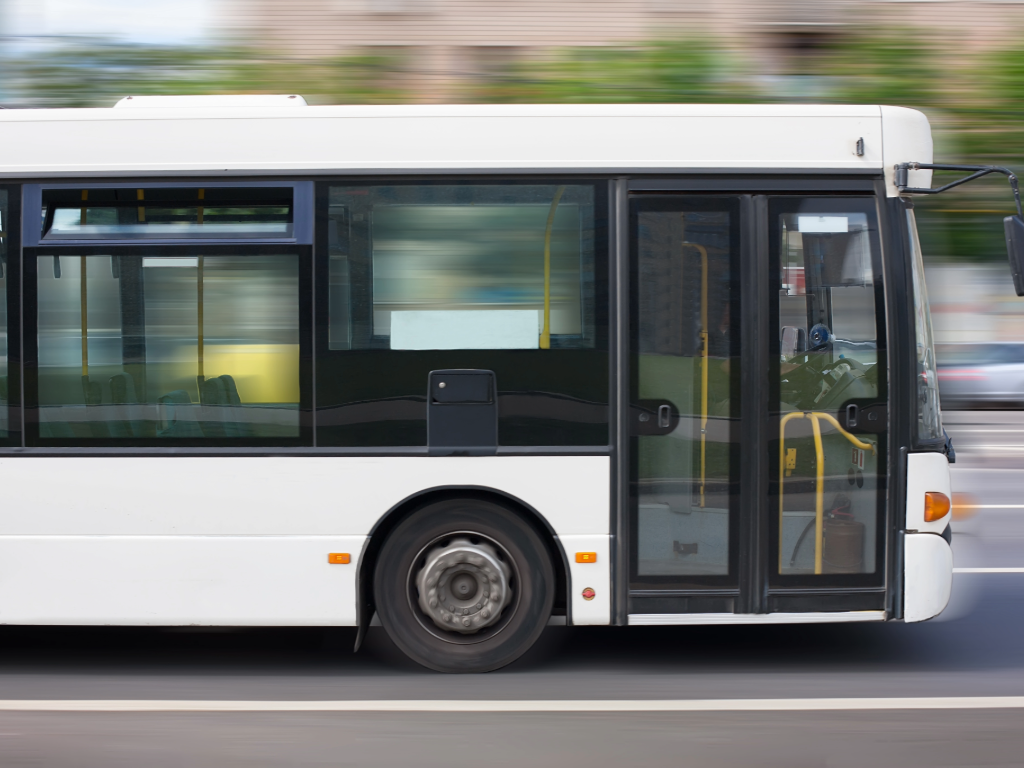 White Bus driving by on city street.