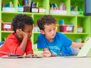 2 Preschool boys looking at book in classroom.