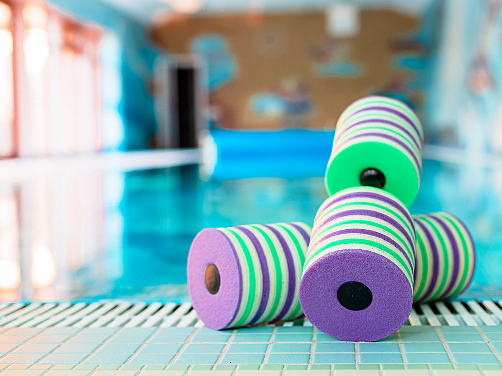 Water weights sitting on edge of indoor pool.