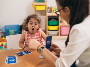 Speech therapist working with little girl to pronounce O.