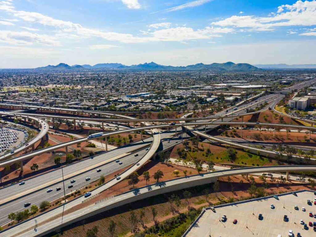 Aerial view of highways and overpasses in Phoenix with mountains in background for article Commuting In Phoenix for newcomers moving to Phoenix.