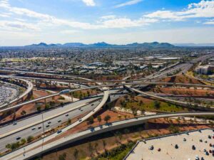 Aerial view of highways and overpasses in Phoenix with mountains in background for article Commuting In Phoenix for newcomers moving to Phoenix.