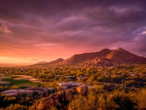 Looking out over the valley of Phoenix with a gorgeous yellow, orange, and purple sunset and large mountain in the background for article Discover the Origins Behind Phoenix's Nickname for newcomers moving to Phoenix.