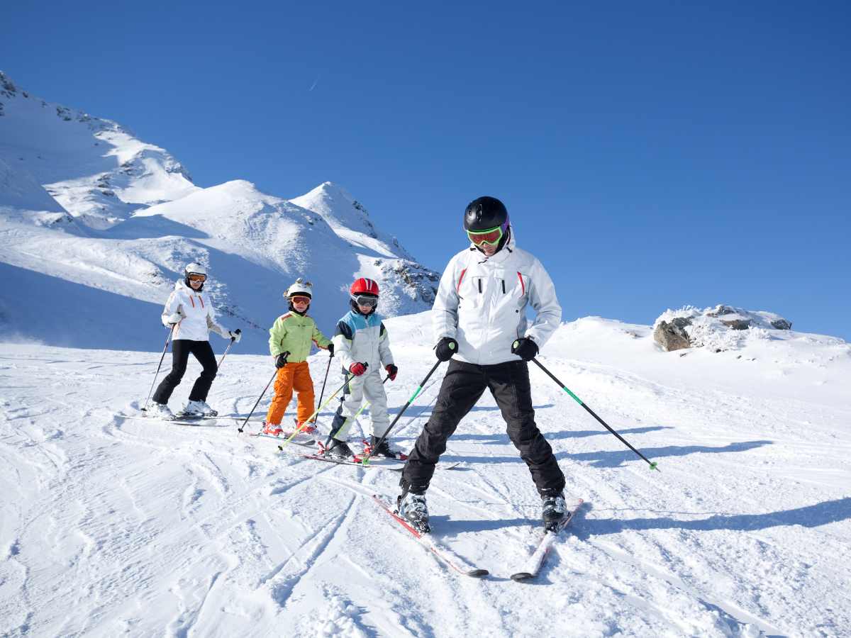 Family of 4 snow skiing down a beginner hill together for article 8 Incredible Places To Go Snow Skiing Near Phoenix for newcomers moving to Phoenix.