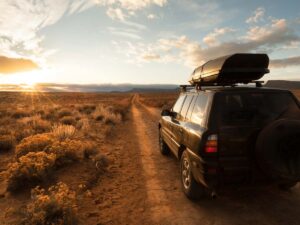 Picture of a sporty SUV with cargo container on roof driving on dusty roads of Arizona for article 5 Easy Steps to Vehicle Registration in Phoenix for newcomers moving to Phoenix.