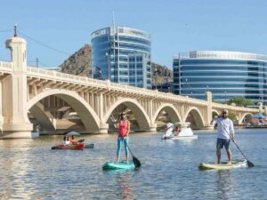 Paddleboarding at Tempe Lake area with red rock in background for article 10 Surprising Things About Phoenix for newcomers moving to Phoenix.