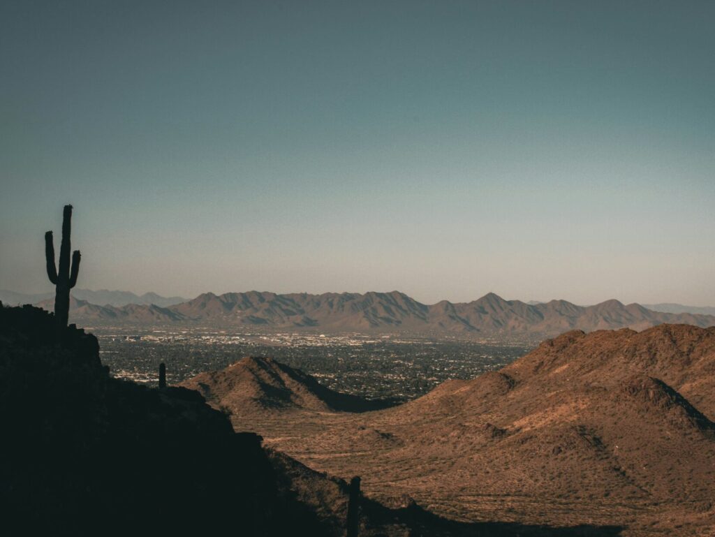 Living in the desert, a landscape of a desert with mountains and a city in the distance